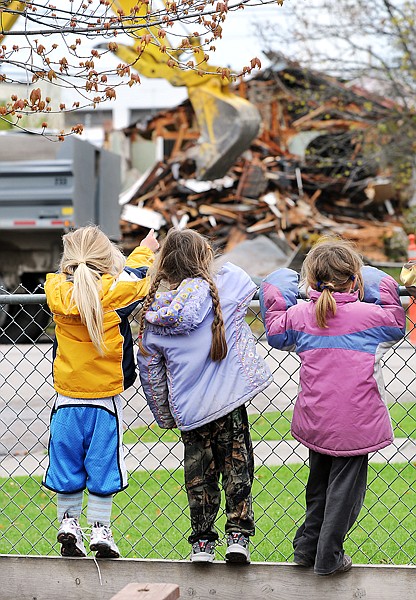 Children at Smith Memorial Day Care line the fence to watch the demolition of the house across the street on Wednesday in Kalispell. The house being torn down will become the new parking lot for the Hockaday Museum.