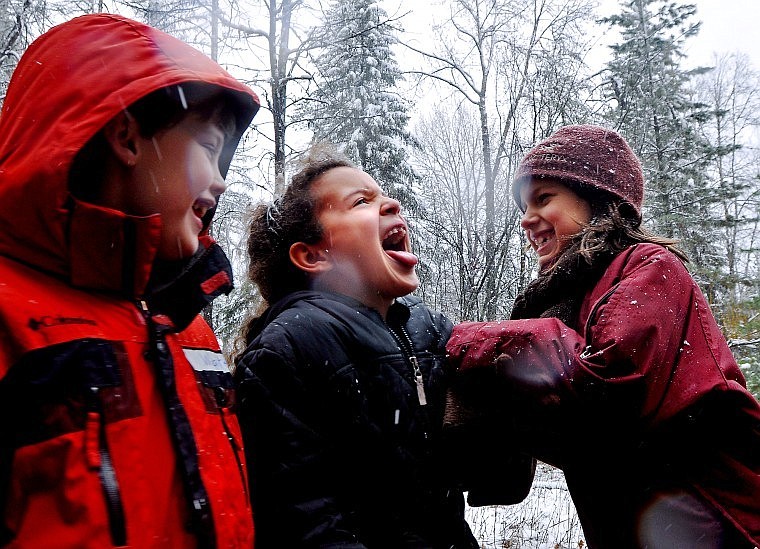 Muldown School second-grader Ashley Nishiyama sticks out her tongue Tuesday afternoon to catch snowflakes while Sareas Decker playfully pushes her and Walter Pearson looks on during a field trip in the snow near the Apgar Visitor Center in Glacier National Park.