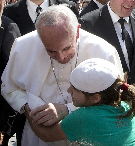 <p>Pope Francis is hugged by a young girl with whom he exchanged skull caps after stepping out of his pope-mobile to walk the last part of his way to the altar, to deliver his weekly general audience in St. Peter's Square at the Vatican, Wednesday.</p>