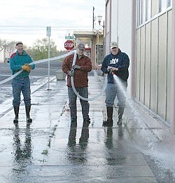 Volunteers hose down the sidewalk next to the post office during the annual Citywide Clean Up Saturday morning.