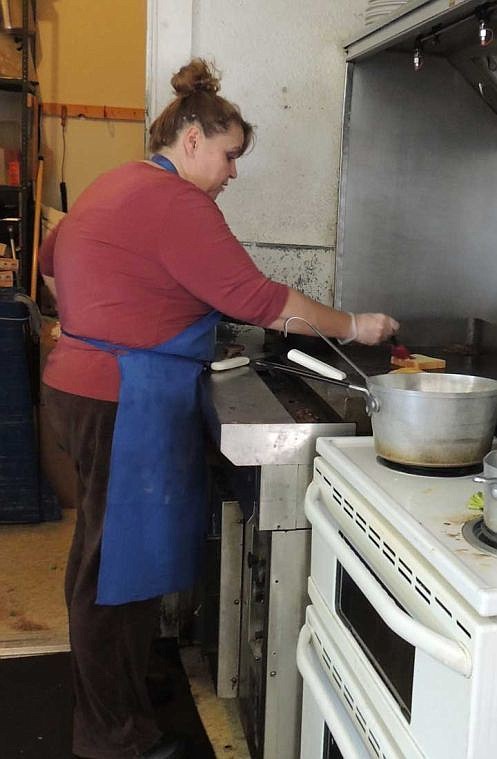 Susie Littlewood, manager of the new Deli-sh Caf&eacute; on highway 26, turns hamburger patties on the grill.