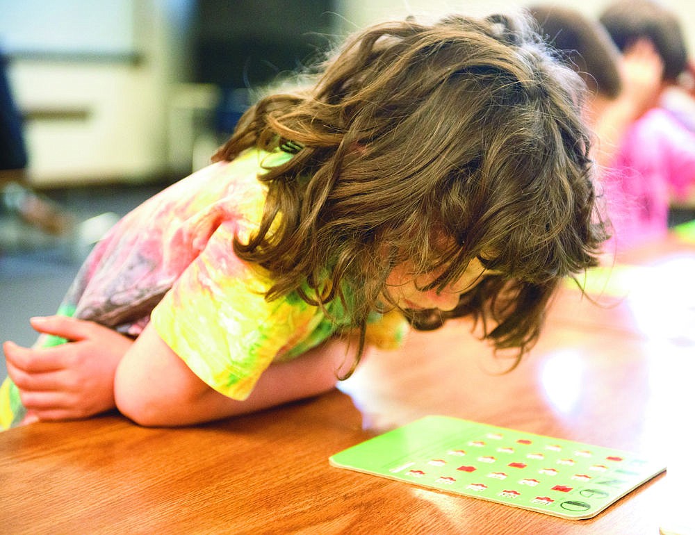 &lt;p&gt;Charessa Elder leans over a bingo board during the last party for the Trout Creek after school program.&lt;/p&gt;