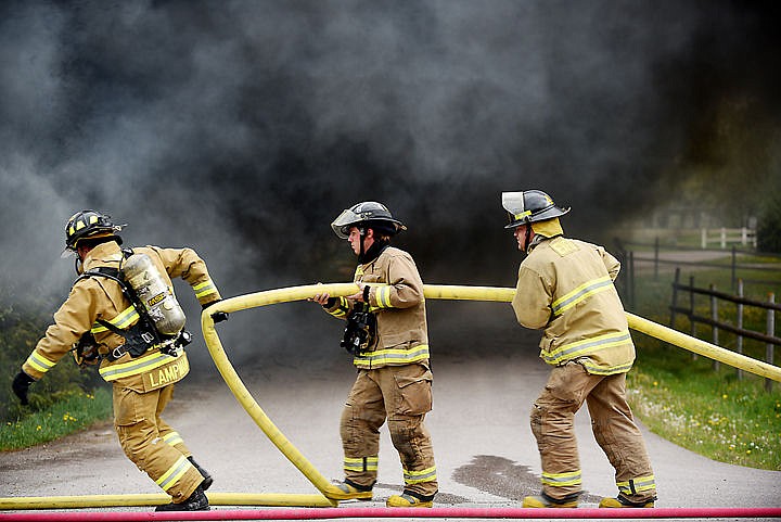 &lt;p&gt;Firefighters carry another hose to a fully involved structure fire on Thursday afternoon, May 14, on Brunner Road southwest of Columbia Falls. Firefighters from Columbia Falls, Evergreen and West Valley responded to the fire. (Brenda Ahearn/Daily Inter Lake)&lt;/p&gt;