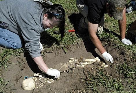 Flathead County reserve deputies Carmen Ramirez, left, and Jim Schneider work to exhume a plastic skeleton during a mock exercise held Saturday at Flathead County Search and Rescue headquarters in Kalispell. Three forensic experts from the Seattle area trained local law-enforcement officers and searchers in crime-scene techniques. Craig Moore/Daily Inter Lake