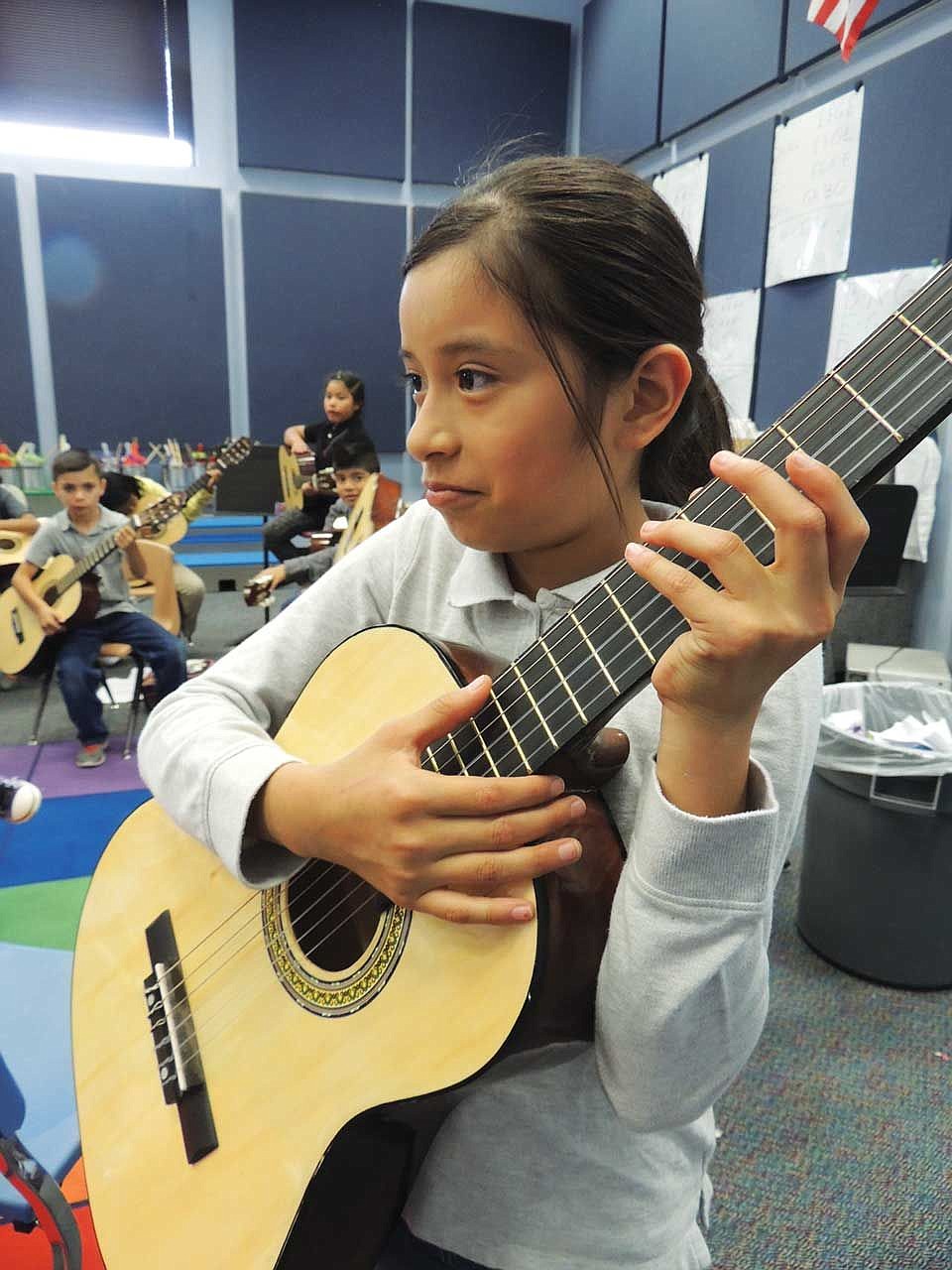 Alexi Martinez watches the teacher intently to match his fingerings on her own guitar.