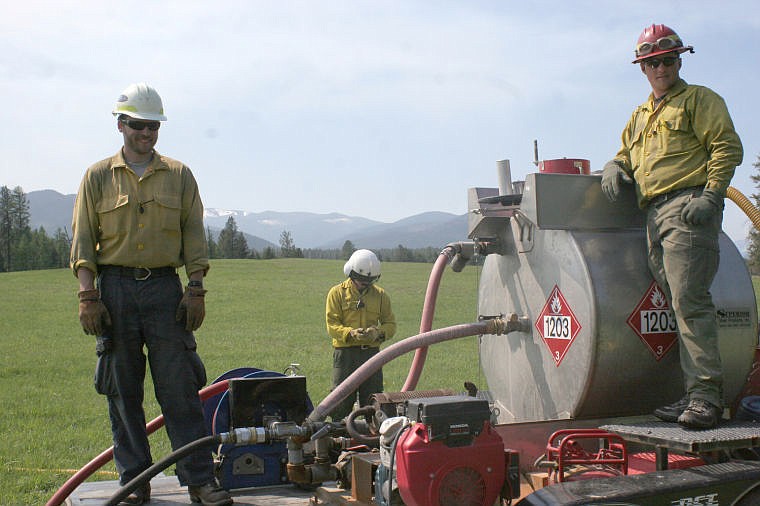 &lt;p&gt;Bau Dobberstein and Rocky Wagoner refill the 55-gallon drum which hung beneath the helicopter. The heli-torch was used to light the prescribed burn.&lt;/p&gt;