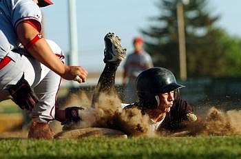 Glacier Twins player Ed Hynes slides into first while Kalispell Lakers first baseman Toby Liechti goes for the tag in the bottom of the third inning during a 2009 season game. Hynes was ruled safe on the play.