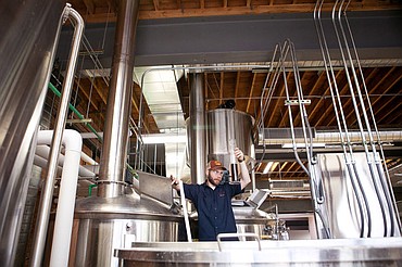 <p>Cole Schneider inspects a sample of the wort Thursday evening at Kalispell Brewing Co. This is about the color the completed beer will be, he said.</p>