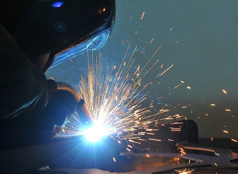 Joshua Boyce welds pieces of a bison historical marker.