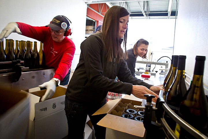 &lt;p&gt;JEROME A. POLLOS/Press Cammie Collins, center, boxes freshly bottled wine off of a conveyor Thursday alongside Trish Kelly as Bob Bolam throws an empty box after preparing bottles for filling. About a dozen volunteers helped kick off the bottling efforts of Coeur d'Alene Cellars wines which will take up more than 20,000 bottles by the end of today.&lt;/p&gt;