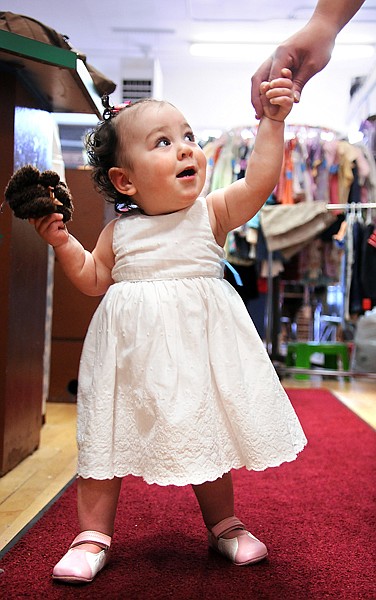 Sofia Pickering of Kalispell, 1, holds the hand of her mother, Leah Pickering, as she makes her way down the red carpet at the dress rehearsal for the Fashion Goes Green II on Monday at Jack and Jill in downtown Kalispell.