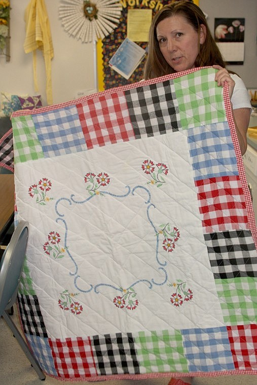 Karin Smith holds a quilt she made for her family business The Family Trunk, which features repurposed vintage items.