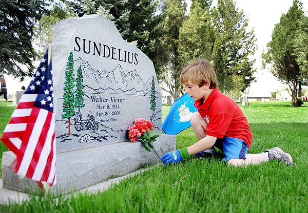 Jabin Turner  places flowers on the grave of Walter Sundelius at the cemetery at Rose Crossing and Whitefish Stage on Monday, May 17.
