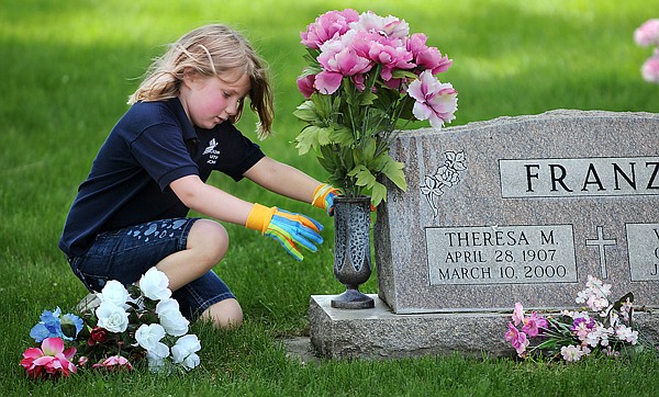 Kaitlyn Thomas and other students in Suzanne Rasmassen first grade help clean up the cemetery at Rose Crossing and Whitefish Stage on Monday, May 17. After the clean up the students added flowers to every grave.