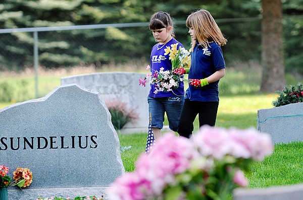 Annie Jensen and Madison Morken place flowers on the graves in the cemetery at Rose Crossing and Whitefish Stage on Monday, May 17.