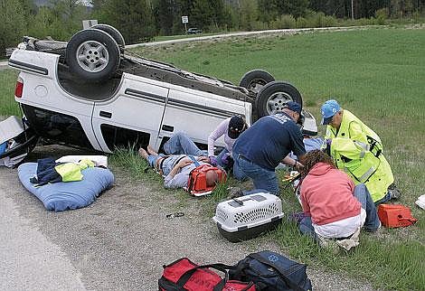 St. Regis and West End Volunteer firefighters work to stabilize two victims in a rollover accident on Interstate 90 last Sunday. Photo by Bruce Charles