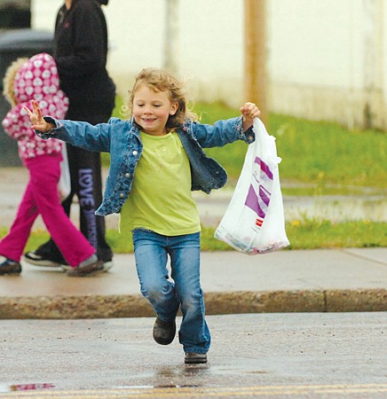 Four-year-old Katie Dolence crosses the street after the Ronan parade was completed with her bag full of candy.