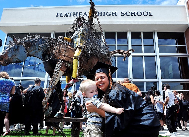 Flathead High graduate Mary Allen hugs her baby brother Tanner Allen following the school's commencement ceremony Saturday afternoon in front of a new sculpture made by Blackfeet artist Jay Laber with the help of four Flathead students.