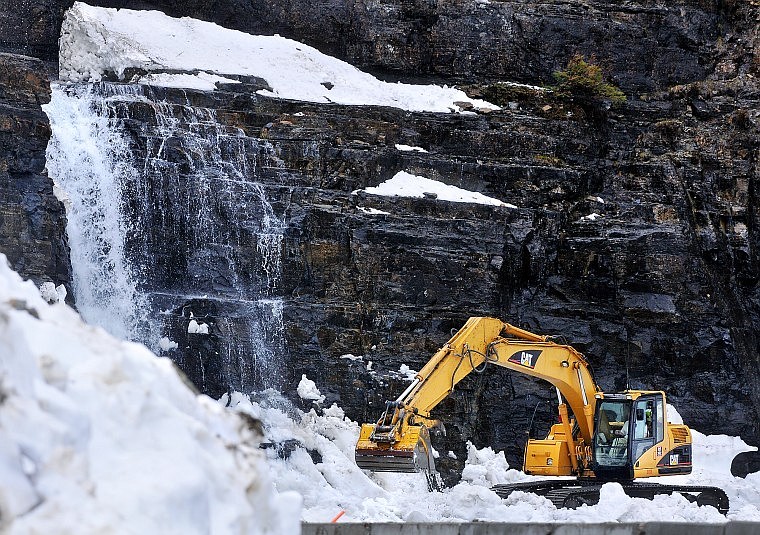 An excavator moves snow Thursday morning off Going-to-the-Sun Road near Triple Arches in Glacier National Park.