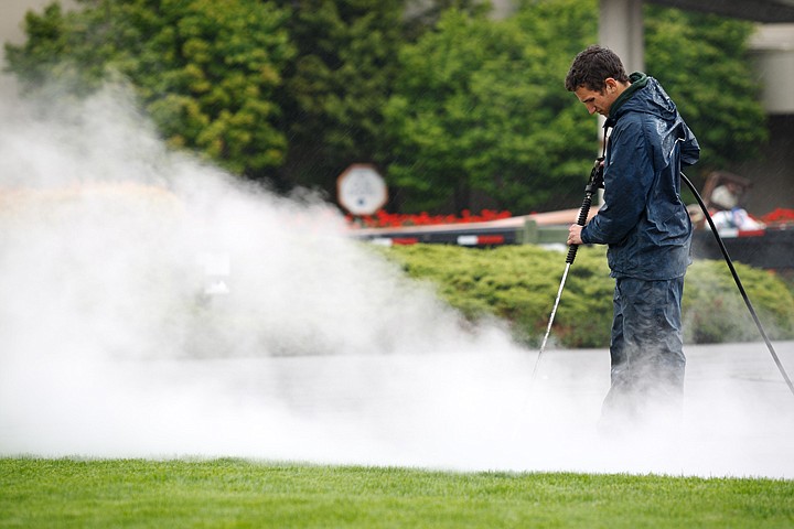 Alex Hendricks, a landscaper for the Coeur d'Alene Resort, uses a power washer to clean a paved surface Thursday.  The cleaning is done prior to an annual application of a protective sealant.