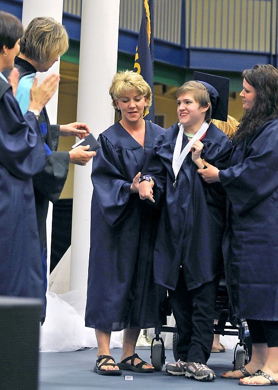 Mikayla Winter is helped to her feet to receive her diploma during Glacier High School&#146;s Commencement Ceremony Saturday afternoon. Winter was born with Aicardi Syndrome, a rare genetic disorder that leaves the corpus callosum, which connects the two sides of the brain, partially or completing missing.