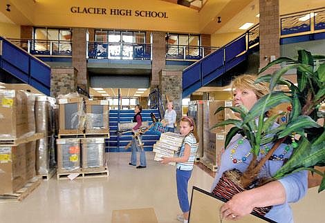 Carrying a plant to her new classroom, Glacier High School teacher Kristyn Morin, right, greets Principal Callie Langohr (not pictured) in the commons area of the new school on Thursday. Morin, who will teach world and U.S. history at Glacier, previously taught those subjects at Flathead High for 16 years. Morin also graduated from Flathead High, as did her daughter, parents and grandparents. Morin was accompanied by fellow Flathead teachers Genia Allen-Schmid, left, and Melanie Dardis, as well as Dardis&#146; daughter, Emily. Karen Nichols photo/Daily Inter Lake