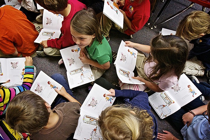 &lt;p&gt;JEROME A. POLLOS/Press Hannah Hall sits with her classmates as members of the North Idaho College wrestling program read a book Wednesday which was purchased through the Shirley Parker Reading Program. The school event marked the 10,000 book donated to every first-grade student in the Coeur d'Alene School District since the program was started in 2002 in partnership with Parker Toyota. The program was was formed in honor of Doug Parker&#146;s late wife, Shirley, who was a supporter of both wrestling and reading. The wrestling team holds a fundraiser at the end of its preseason to support the program. The players collect pledges toward their completion of a mountain climb in Hope, Idaho, typically raising about $1,000 that goes toward the purchase of books for every first-grader in the Coeur d&#146;Alene School District. Each week during the season, NIC wrestlers and coaches visit a local elementary school to read to the first-graders. The children are encouraged to take their book home to continue practicing their reading skills in addition to receiving a bookmark and poster of the wrestling team.&lt;/p&gt;