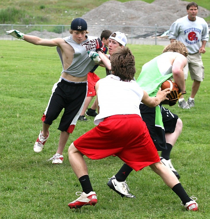 Tucker Smith (left) lunges towards his brother Billy Smith (center) during Superior High School Football Camp Thursday afternoon.