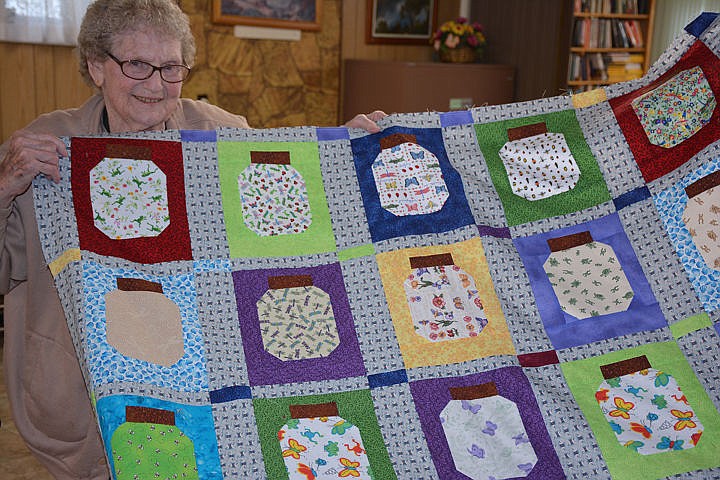 &lt;p&gt;Ayleen Bain holds up her Bugs in a Jar quilt top.&lt;/p&gt;