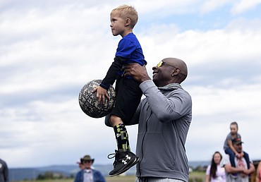 <p>Jerry Rice lifts four-year-old Jackson Pelc in the air to shoot a basket during the Play 60 Challenge at Glacier High School on Saturday. (Aaric Bryan/Daily Inter Lake)</p>