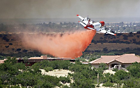 &lt;p&gt;A plane drops slurry near houses after a fire sparked on Fort Huachuca in Sierra Vista, Ariz., on Friday.&lt;/p&gt;