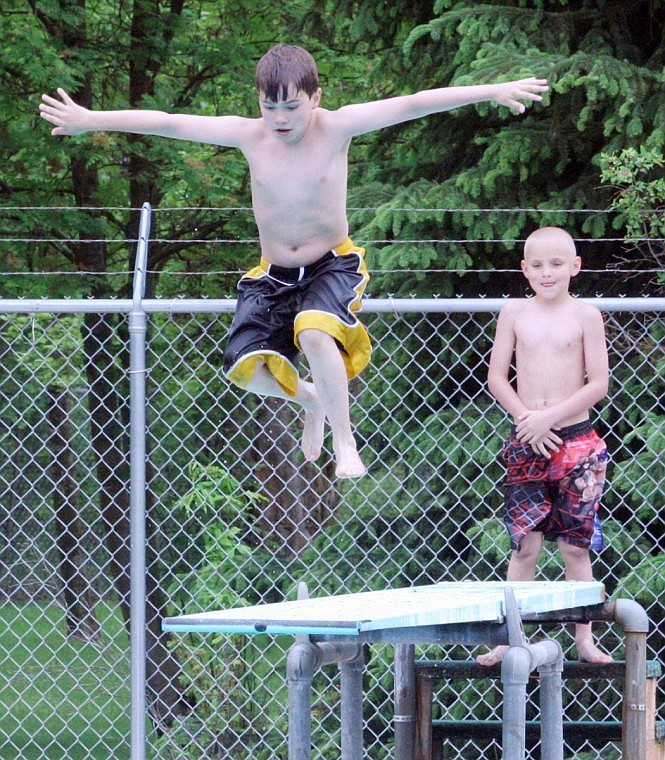Mason Frost jumps off the diving board while Mark Coleman patiently waits his turn.