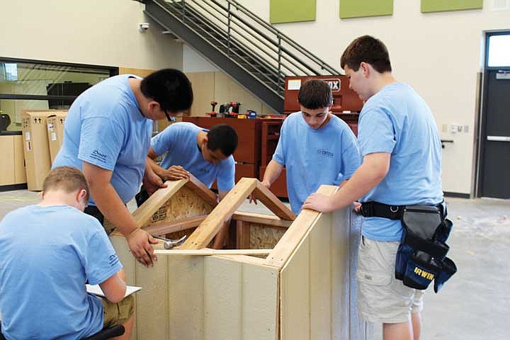 Students in the skilled trades class cluster around a partially finished doghouse during a session at the Columbia Basin Technical Skills Center.