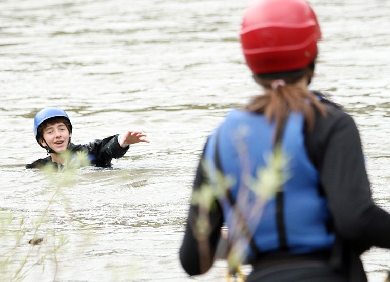 Will Baker, left, reaches out for a helping hand from Tabitha Lee, right, in the Clark Fork River on Monday. The two were practicing river rescues as part of the technical training given to the Camp Bighorn summer staff before the summer camps start next week.