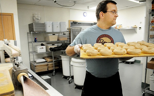 Patrick Levitt of the Montana Bagel Company transfers a tray of formed bagel dough to a baking rack on Friday afternoon. Levitt said on average they make 25 dozen bagels for each store.