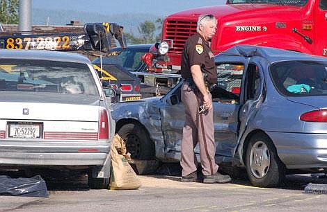 Flathead County deputy coroner Jim Browder examines a Ford Contour involved in a fatal crash just after 5 p.m. Thursday at the intersection of U.S. 93 and Montana 82. The Ford&#146;s driver, a 29-year-old man from Wisconsin, died at the scene. His passenger and the driver of the Oldsmobile were injured. According to the Montana Highway Patrol, the crash, which occurred when the Oldsmobile&#146;s 83-year-old driver ran a red light, forced authorities to re-route traffic through the parking lot of the White Oak C-Mart for more than 1 1/2 hours. Nicholas Ledden/Daily Inter Lake