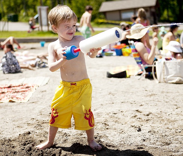 Bradley Hudson, 4, takes aim as he shoots his water cannon during the first day of summer on City Beach in Whitefish Tuesday afternoon.