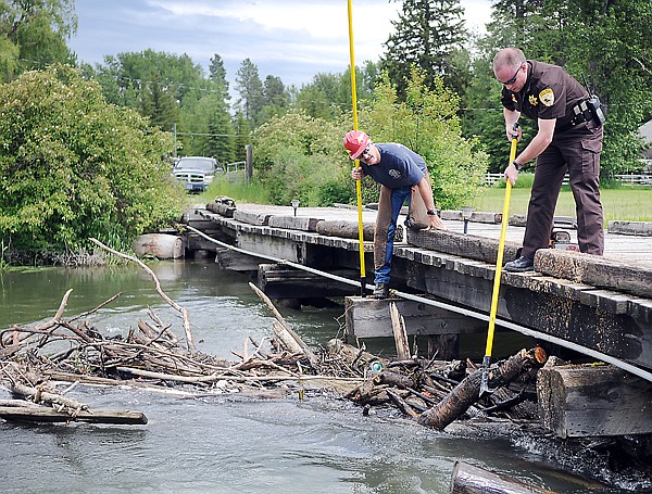 &lt;p&gt;Undersheriff Jordan White and Lincoln Chute of the Office of
Emergency Services work to remove logs trapped at a bridge crossing
the Whitefish River near River Road on Thursday afternoon in
Evergreen.&lt;/p&gt;