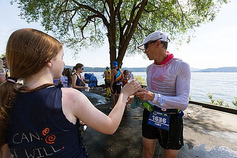 &lt;p&gt;Rachel Foster, a volunteer at an aid station along Coeur d&#146;Alene Lake Drive, hands a cup of water to a soaking wet Curt Biddulph, a male 45-49 age group competitor, during the marathon portion of Sunday&#146;s Ironman.&lt;/p&gt;