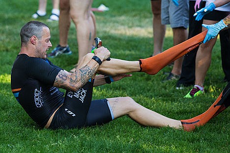 &lt;p&gt;A triathlete is helped in removing his wet suit in the swim-to-bike transition area.&lt;/p&gt;