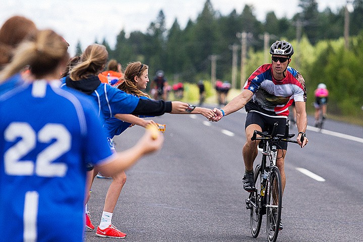 &lt;p&gt;SHAWN GUST/Press&lt;/p&gt;&lt;p&gt;Maggie Davies, a volunteer with the Coeur d&#146;Alene girls soccer team, hands off an item for caloric intake and energy to triathlete Travis Lyon at an aid station along U.S. 95 near Fighting Creek.&lt;/p&gt;