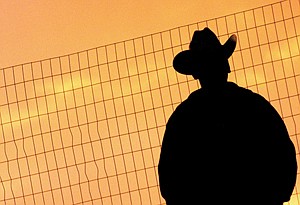 A lone cowboy watches the Mission Mountain PRCA Rodeo as the sun sets last weekend in Polson.