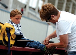 Four-year-old Riley Knutson gets his spurred laced up by his great aunt Penny O'Hern before the youth events of the Mission Moutain PRCA Rodeo last weekend.