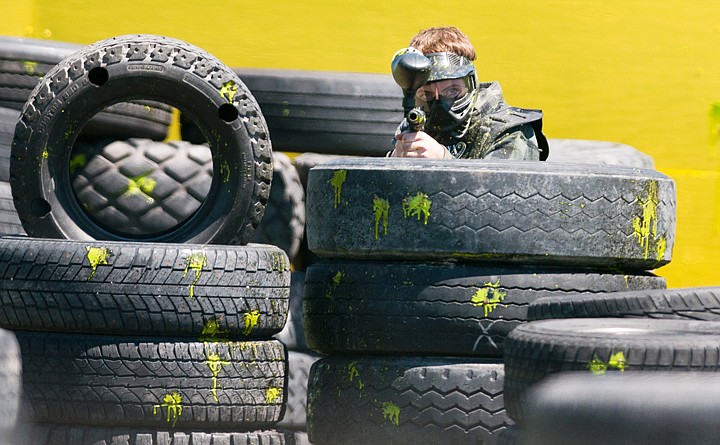 <p>Cole Lusher searches for opponents from behind the cover of tiresThursday afternoon during a paintball game at Montana Action Parks outside of Columbia Falls. Thursday, June 28, 2012 in Columbia Falls, Montana.</p>