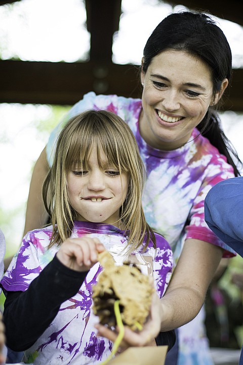 &lt;p&gt;SHAWN GUST/Press Jessica Lamb, second grade teacher at Mullan Trail Elementary, helps Lilly Day as the student smothers a pinecone with peanut butter while making a bird seed feeder Wednesday at Falls Park in Post Falls. The annual field trip, in its third year, allows students lessons in the area's local environment that include a nature hunt and comparing natural and manmade features, as well as making their own pinecone bird feeders.&lt;/p&gt;