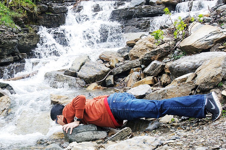 <p>Andy Tran of Scottsdale, Ariz., takes a drink out of Haystack Creek Friday afternoon in Glacier National Park. June 21, 2013 in Glacier National Park, Montana. (Patrick Cote/Daily Inter Lake)</p>