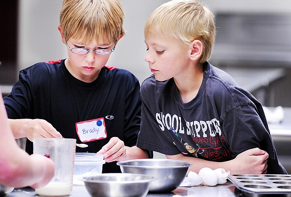 Brady Schultz, 10, and AJ Weller, 10, both of Kalispell, left to right, measuring ingredients as they prepare to mix muffins at the at the Kids College Junior Chefs Training on Monday at FVCC.