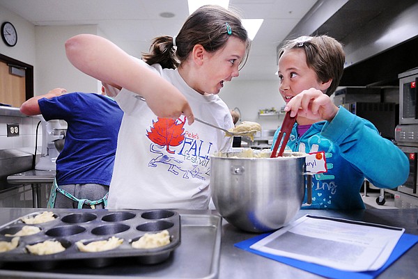 Claire Bradley, 10, and Lauryl Himsl, 10, both of Kalispell, left to right, making cinnamon, poppy, banana muffins at the Kids College Junior Chefs Training on Monday at FVCC.