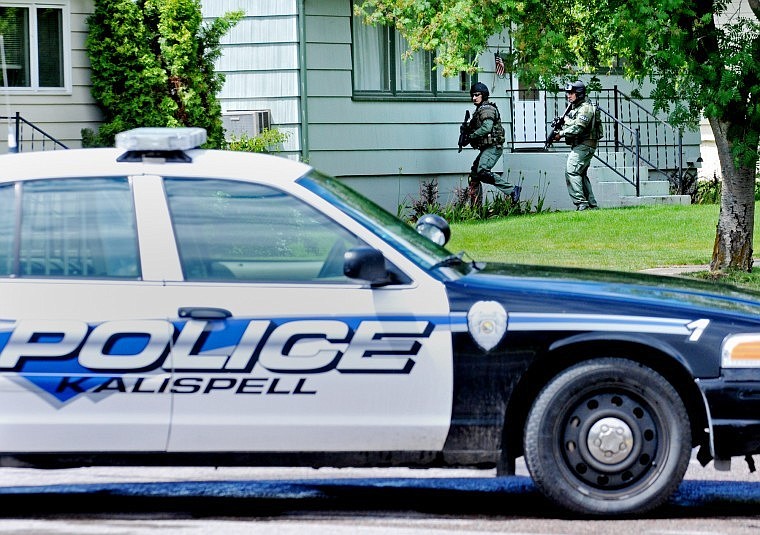 Kalispell Police Special Response Team officers approach a home on Fourth Avenue West North on Friday afternoon. Police officers arrived on scene at 11:30 a.m. and were on hand until the man voluntarily surrendered at 5 p.m. Nearby homes were evacuated and streets blocked off. The man, who was not charged with a crime, was treated for minor self-inflicted wounds.