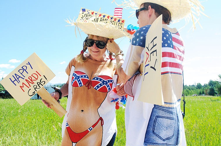 <p>Susan Ames of Daphne, Ala., right, helps Carol Dolan-Groebe of Fairhope, Ala., attach an American flag to her straw hat Thursday afternoon during the Fourth of July parade in Polebridge. Dolan-Groebe has a cabin in Polebridge that she stays at during the summer.</p>